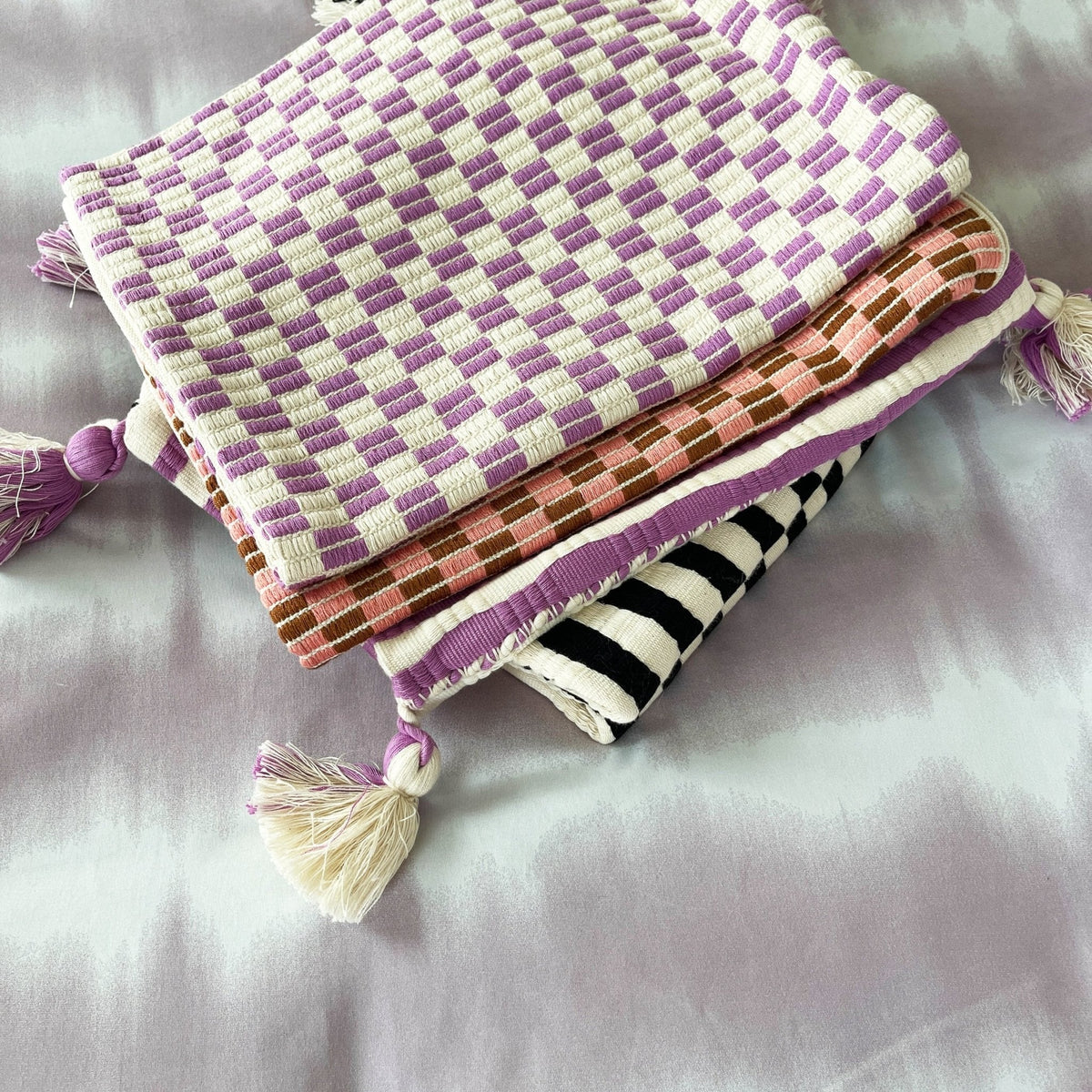 Stack of handwoven Guatemalan textiles including the pink and umber checkered brocade