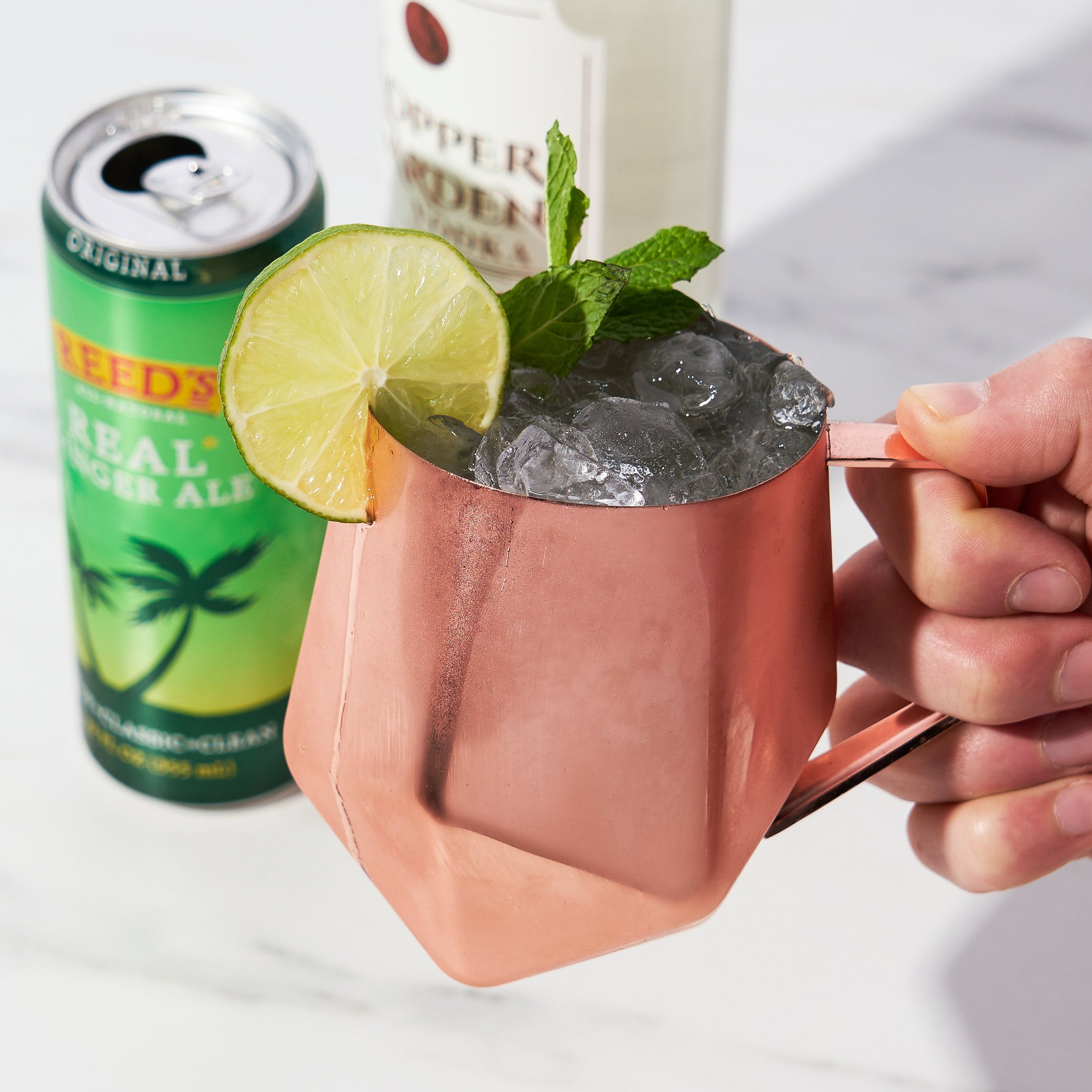 Copper Moscow Mule mug filled with cocktail, lime, and mint garnish