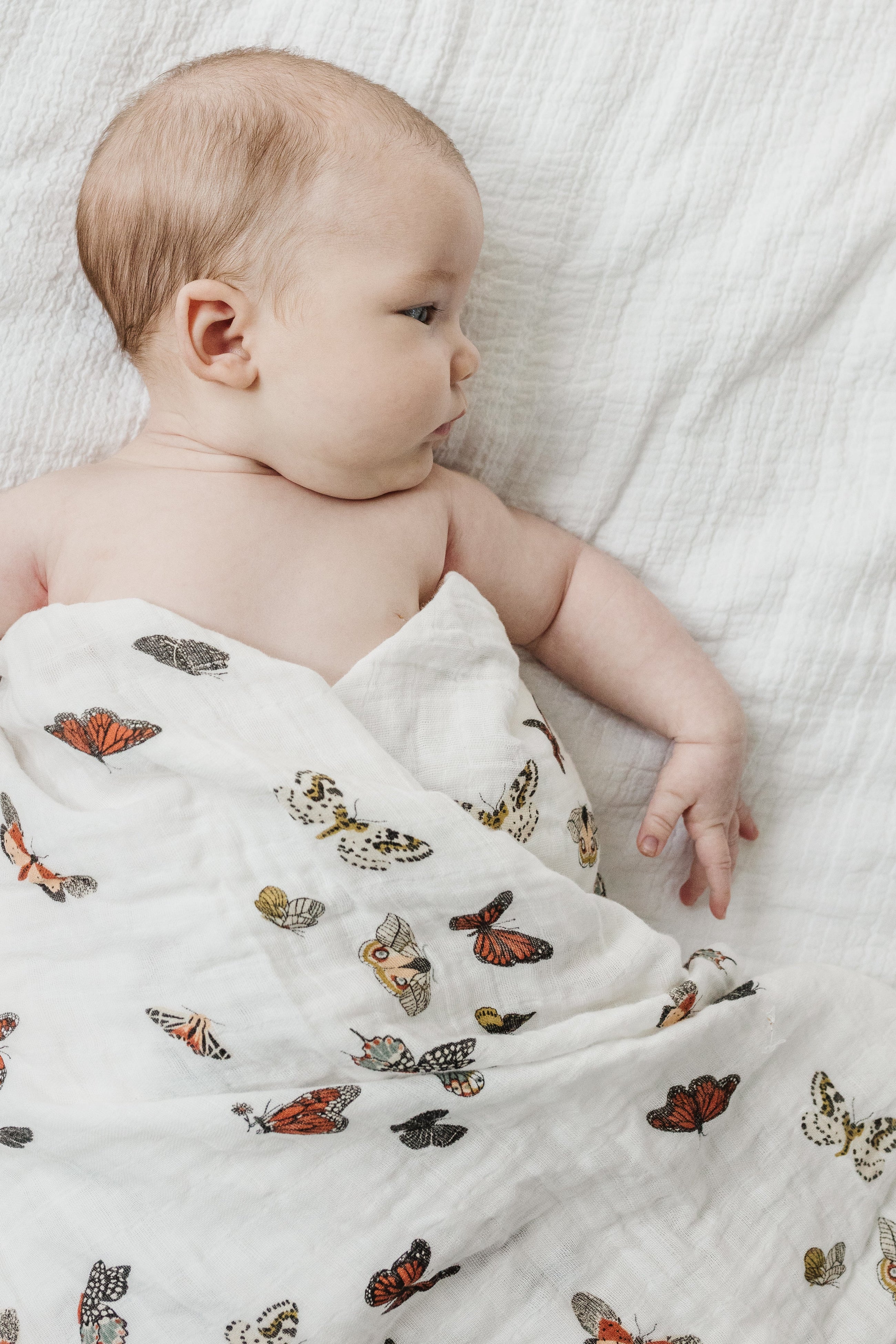 Cotton muslin swaddle with butterfly print folded on crib