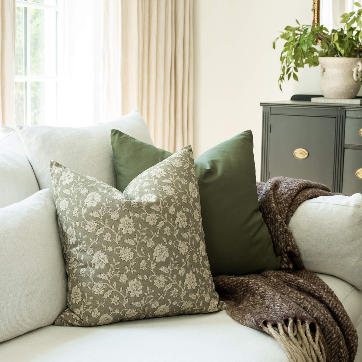 Esme sage and taupe botanical throw pillow cover on a sofa