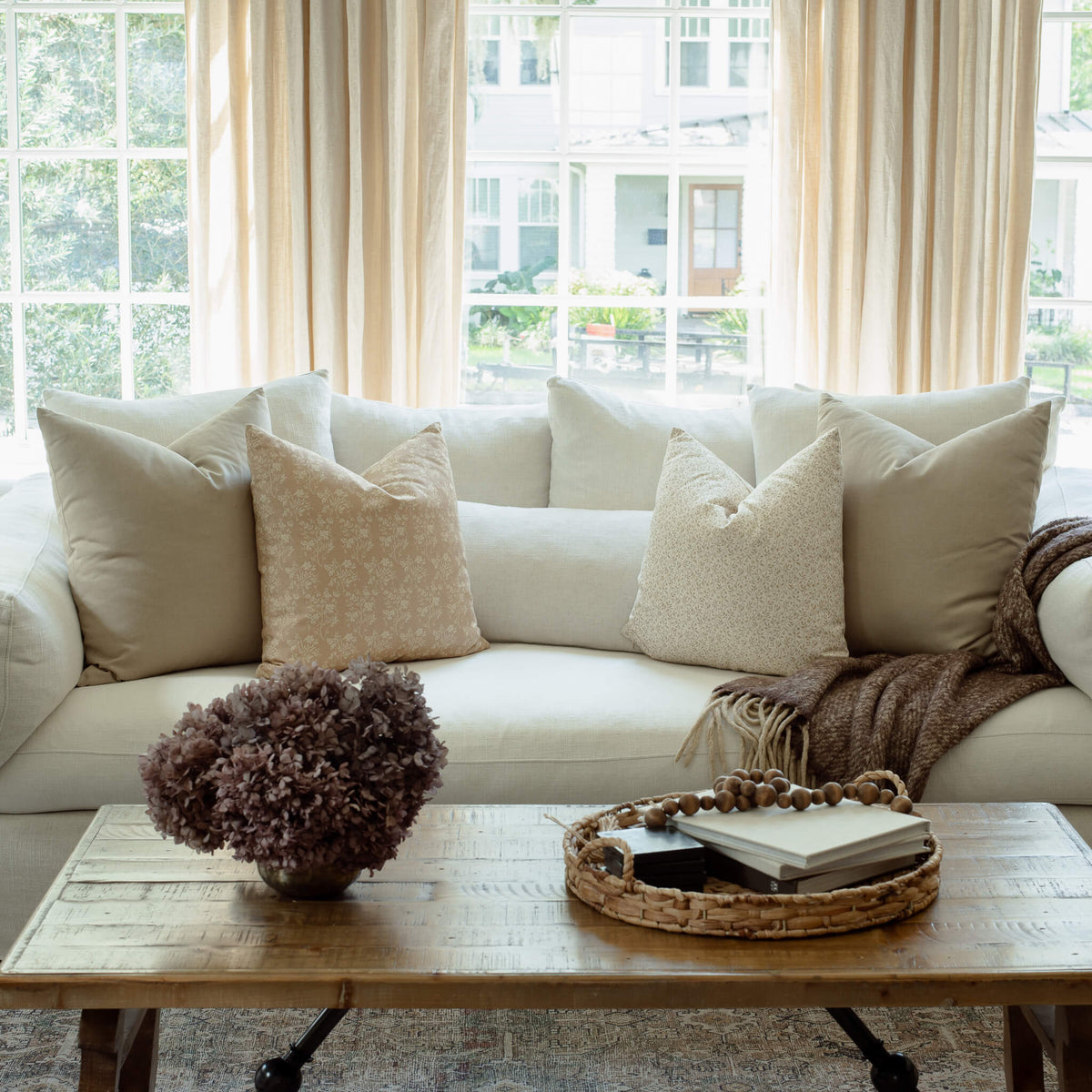 Mila tan floral pillow with sage ditsy pillows on an organic modern sofa