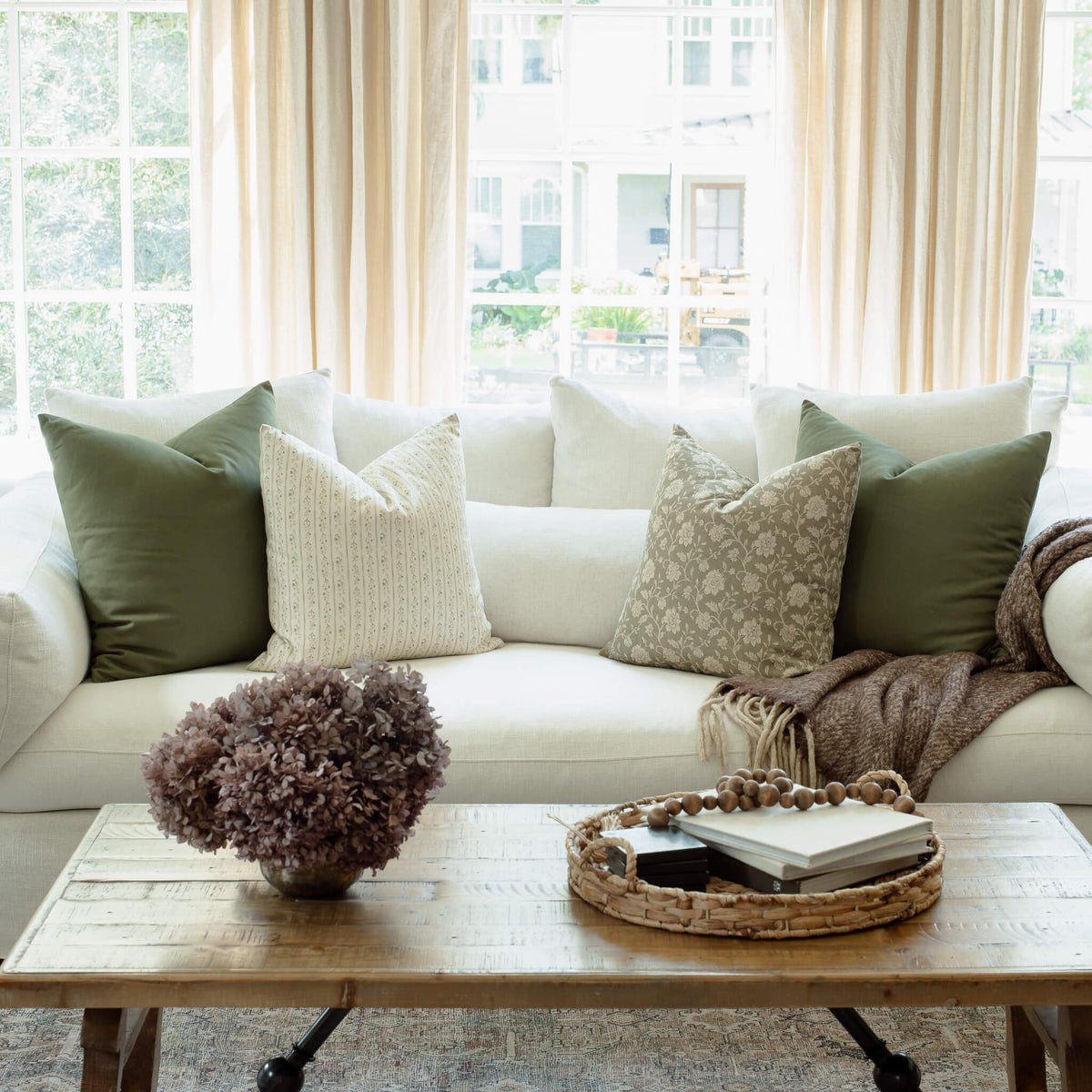 Esme sage green floral pillow styled on a neutral sectional
