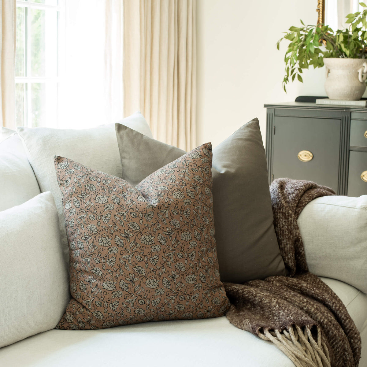 Odette terracotta pillow with a blue paisley throw pillow on a sofa