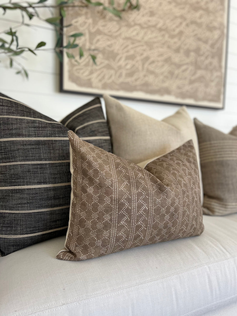 four pillows on a white couch with a brown painting behind the couch