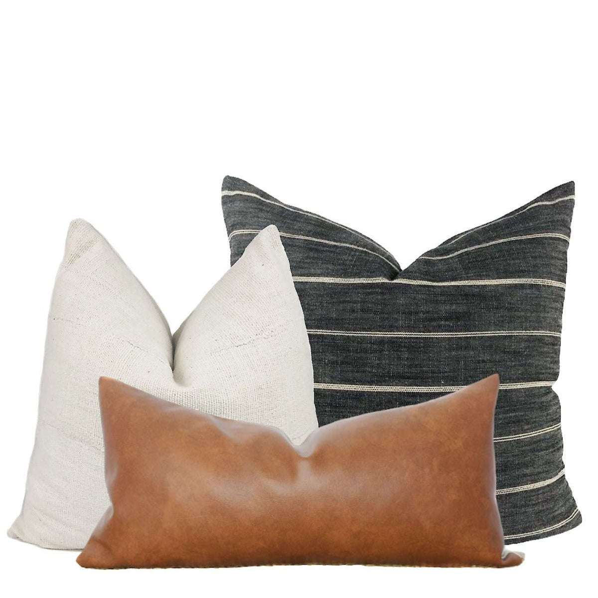 Cream mudcloth, grey stripe and faux leather pillow covers styled on a brown couch