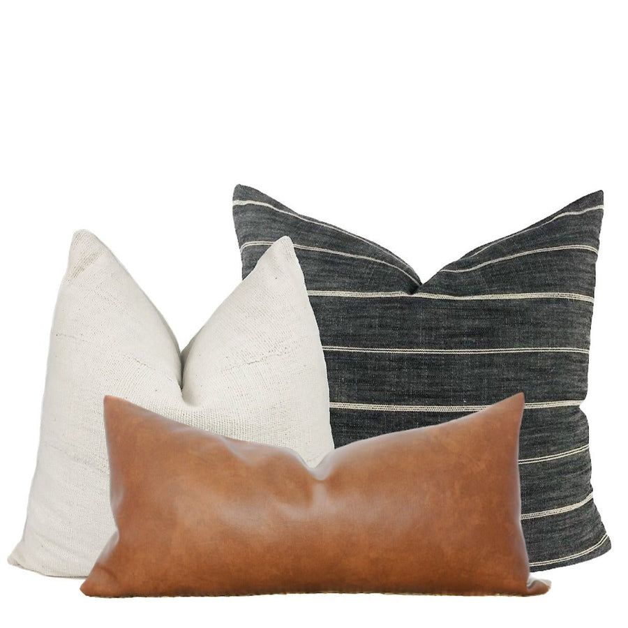 Cream mudcloth, grey stripe and faux leather pillow covers styled on a brown couch