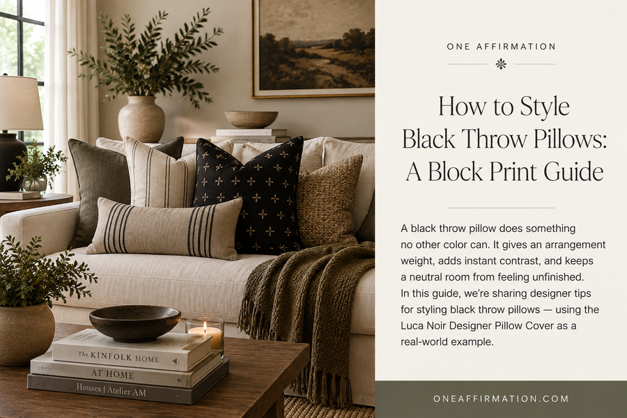 Black block print throw pillow styled with neutral and olive accent pillows on a cream sofa in a warm, layered living room.