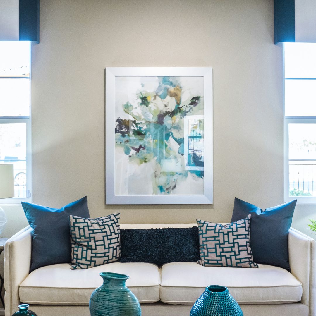 white couch with blue designed pillows and art on the back wall