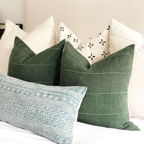 Green and cream designer throw pillows on a bed