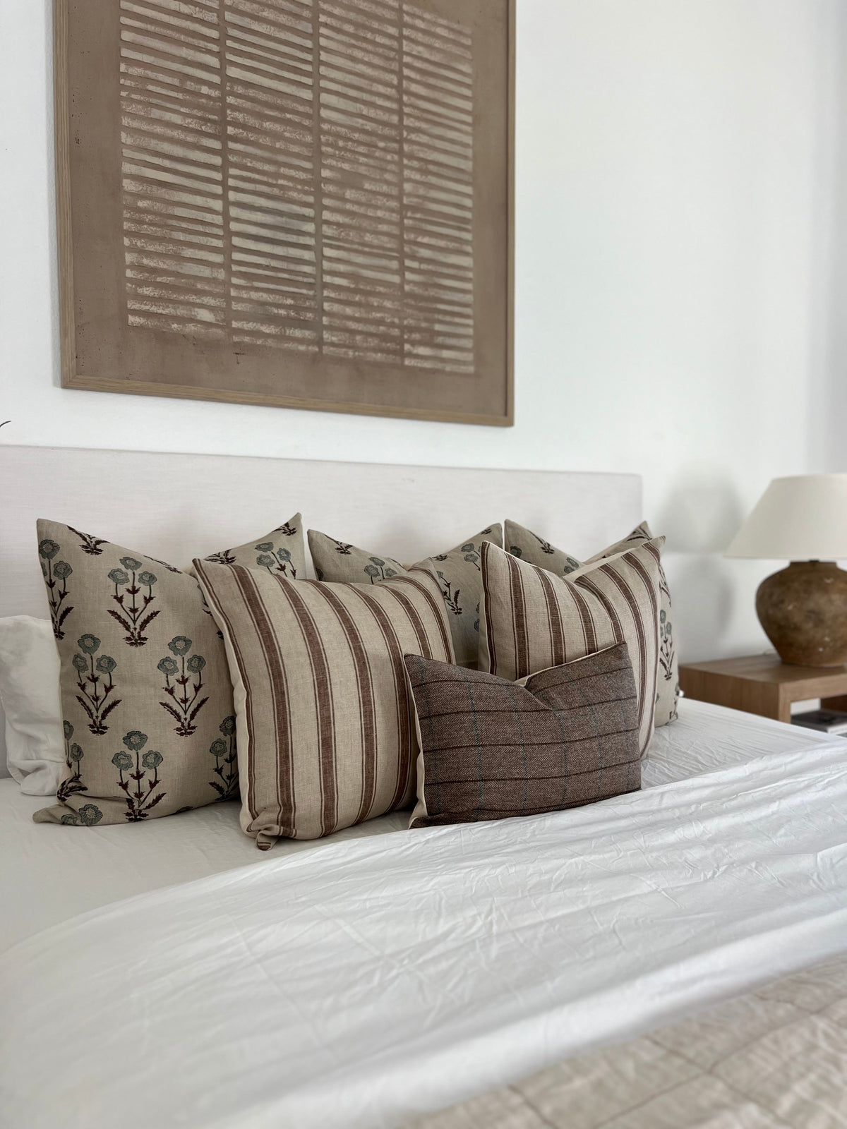 Neutral designer throw pillows styled on a bed in a luxury home interior
