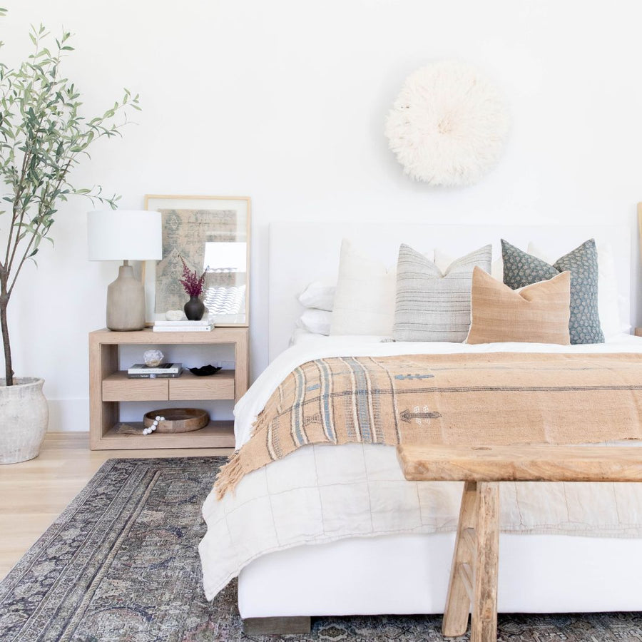 Bed with throw pillows and wooden table in front of it