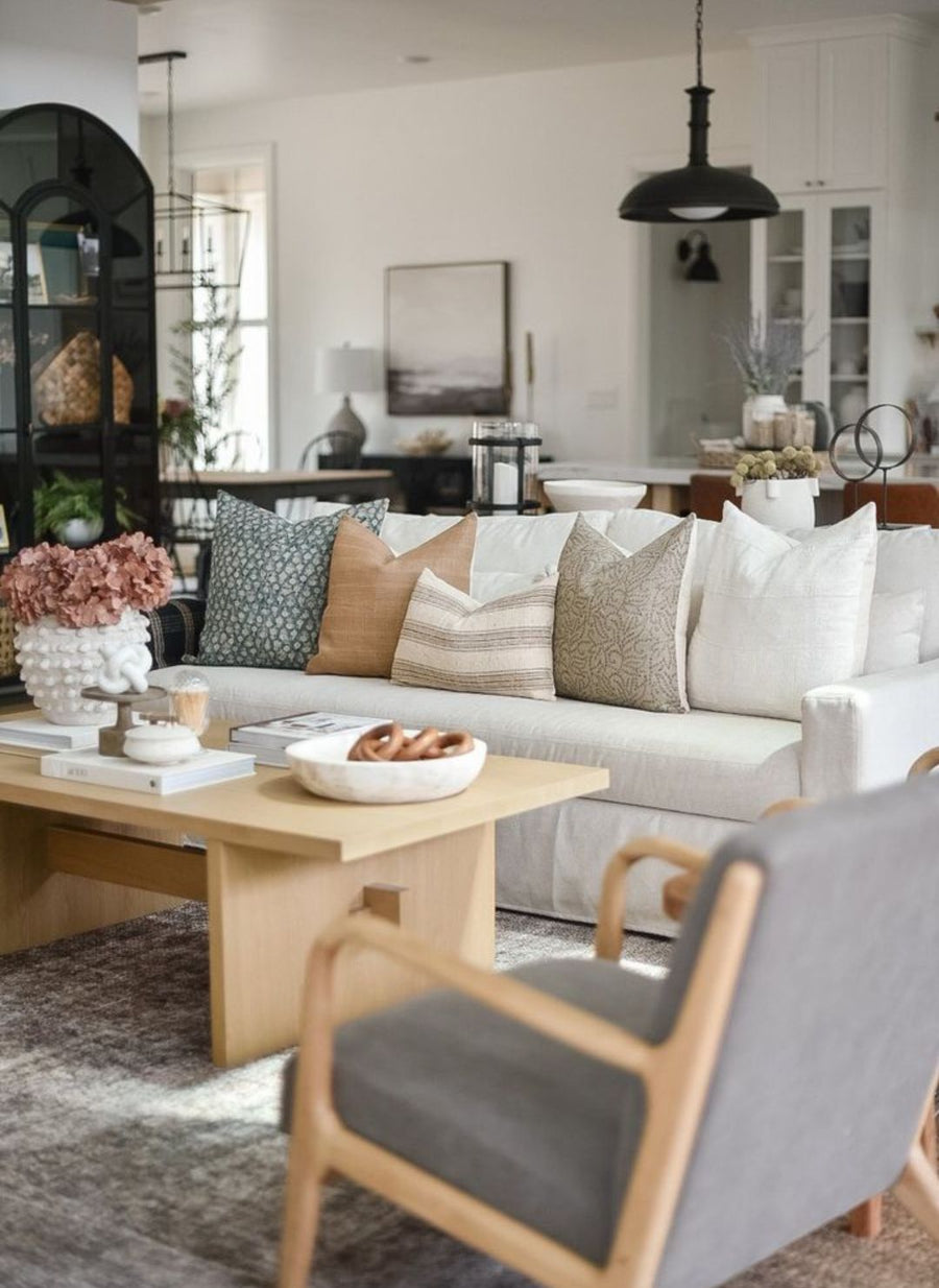 designer throw pillows all spread out on a couch with an open book in front of them