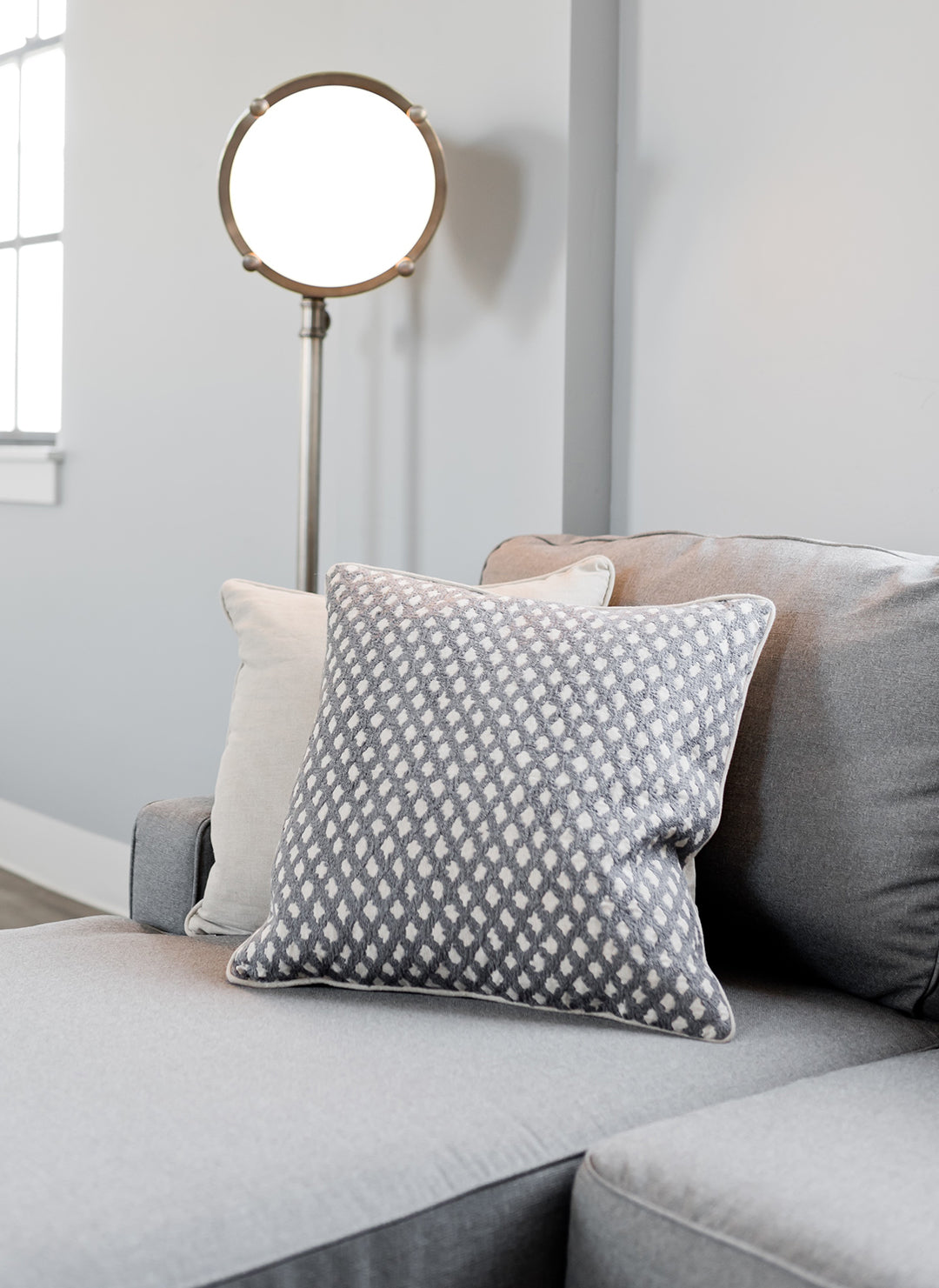 couch pillows set on a couch with a circular mirror in the background