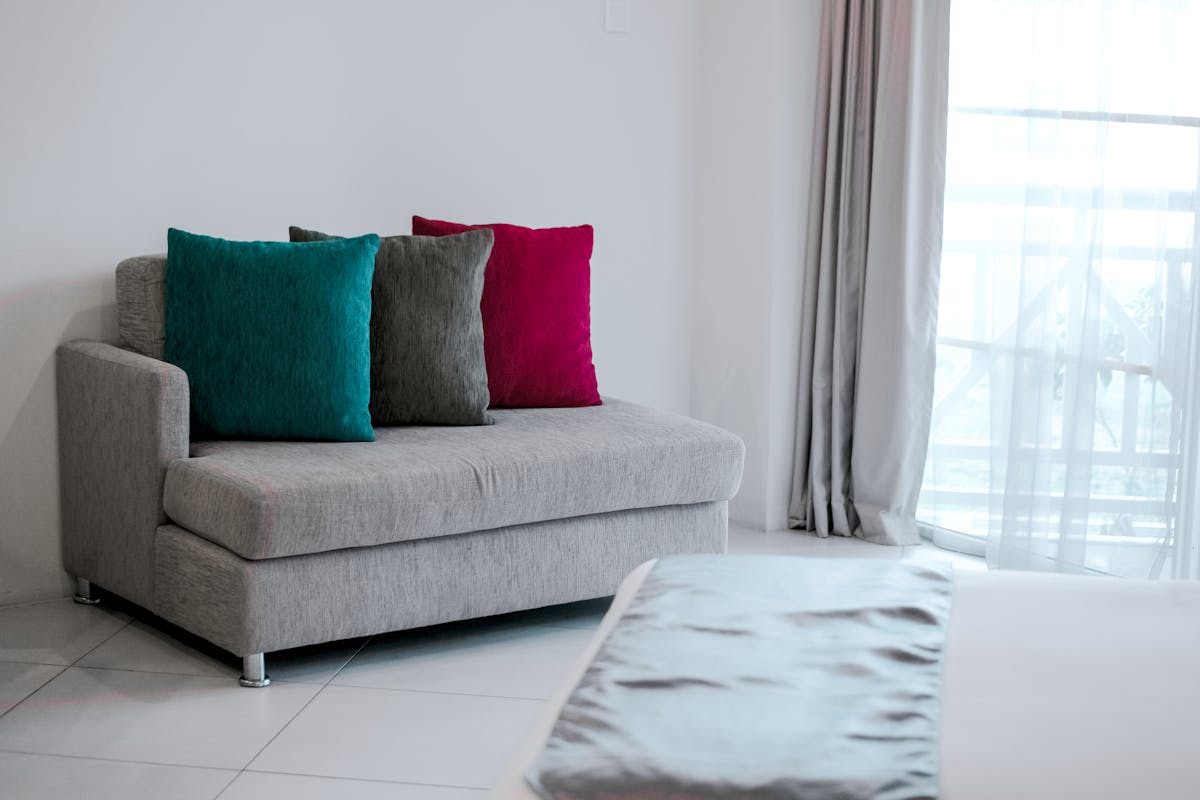 a bunch of colorful pillows sitting on a couch in a white room