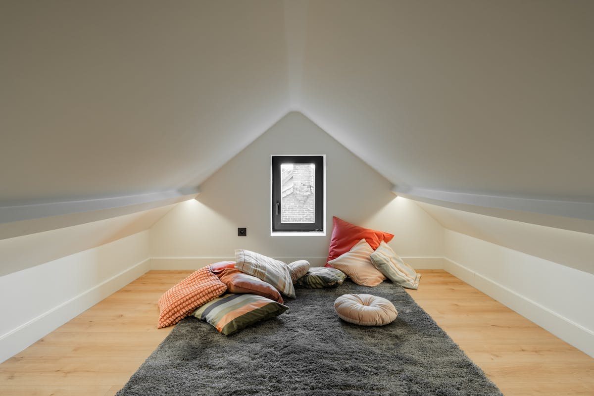 an attic area filled with a ton of pillows and throw rugs