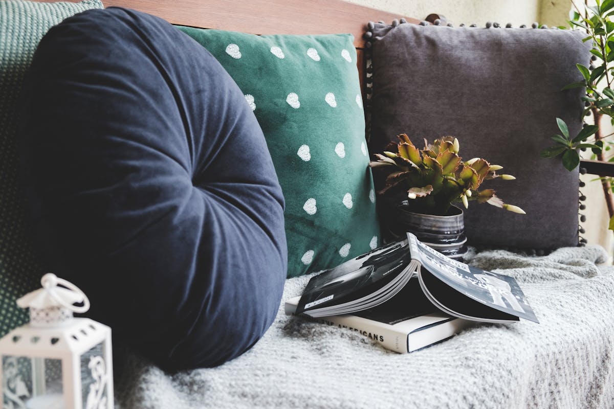 a bunch of stylish pillows on a couch with some books