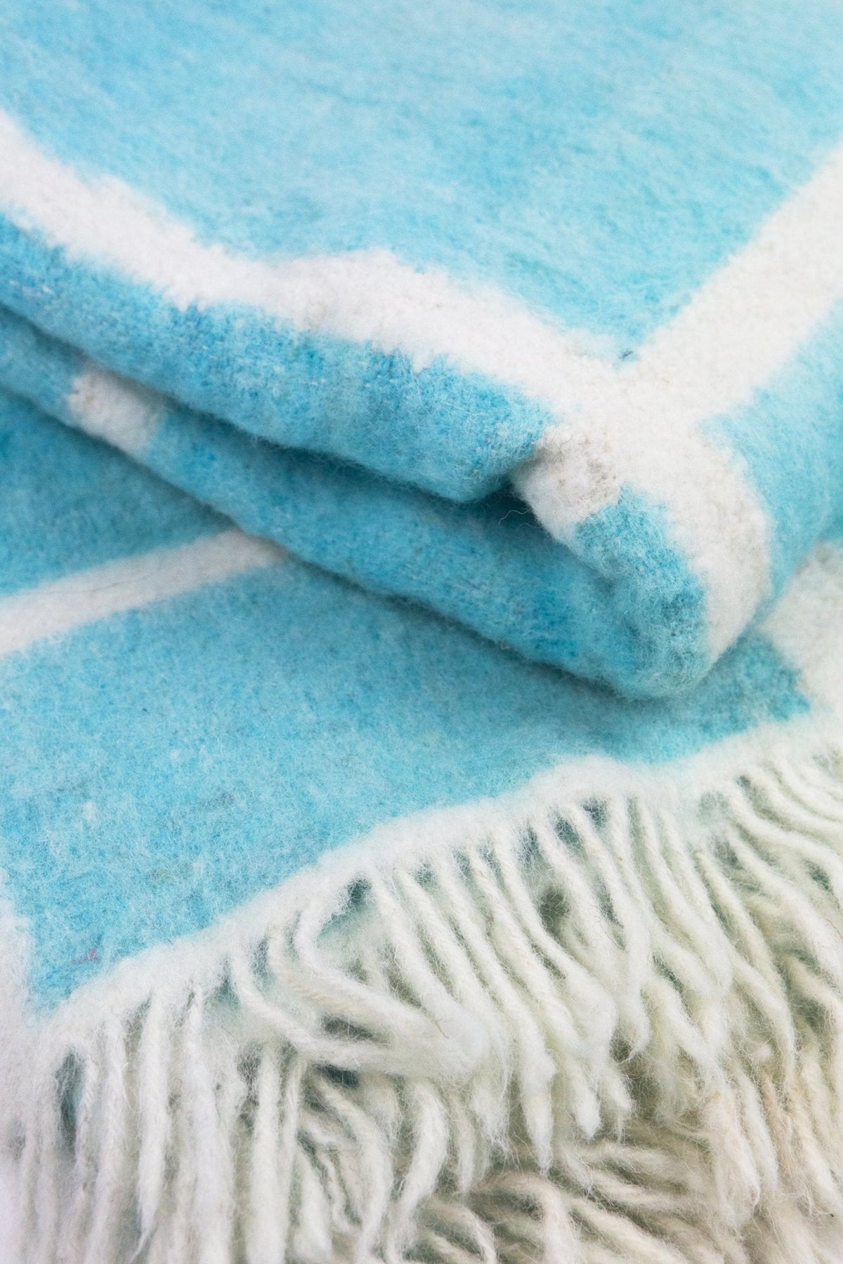 Momos Grid felted wool blanket in aqua blue and natural white, folded