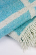 Close-up of the Momos Grid felted wool blanket in aqua blue and white