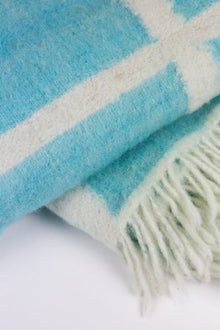 Close-up of the Momos Grid felted wool blanket in aqua blue and white