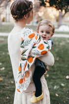 Baby wrapped in Clementine citrus print muslin swaddle