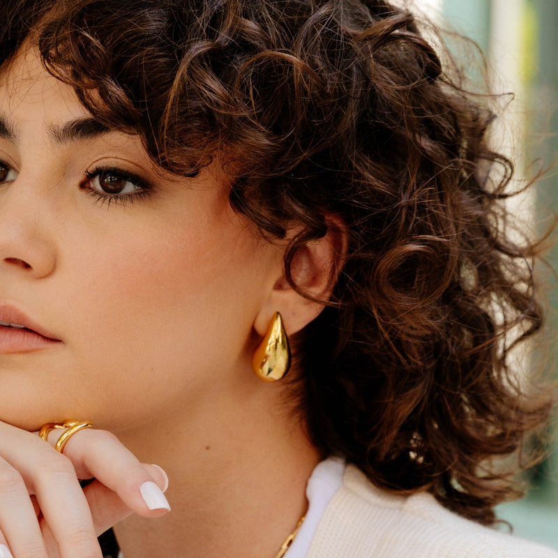 Statement raindrop-inspired gold earrings on model