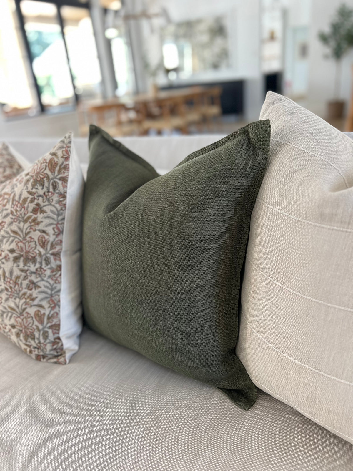 Olive linen pillow on a sand colored sofa.
