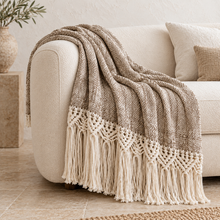 Brown Mountain macramé cotton throw draped over an ivory armchair