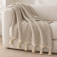 Cream organic cotton throw with fringe on an ivory armchair