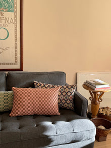 Checkered brocade pillow in pink and umber styled in a home interior