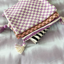 Stack of handwoven Guatemalan textiles including the pink and umber checkered brocade