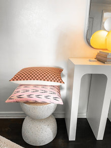 Checkered brocade pillow in pink and umber styled in a living room