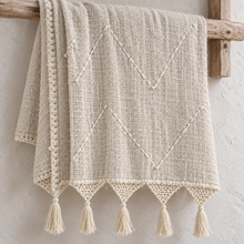 Cream organic cotton throw with macramé fringe on a rustic rail