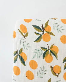 Citrus fruit and leafy pattern crib sheet on mattress