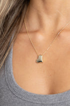 Close-up of gold Susie Heart Necklace against neutral background