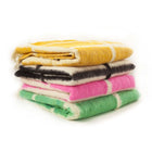 Stack of handwoven Momos Grid felted wool blankets in assorted colors