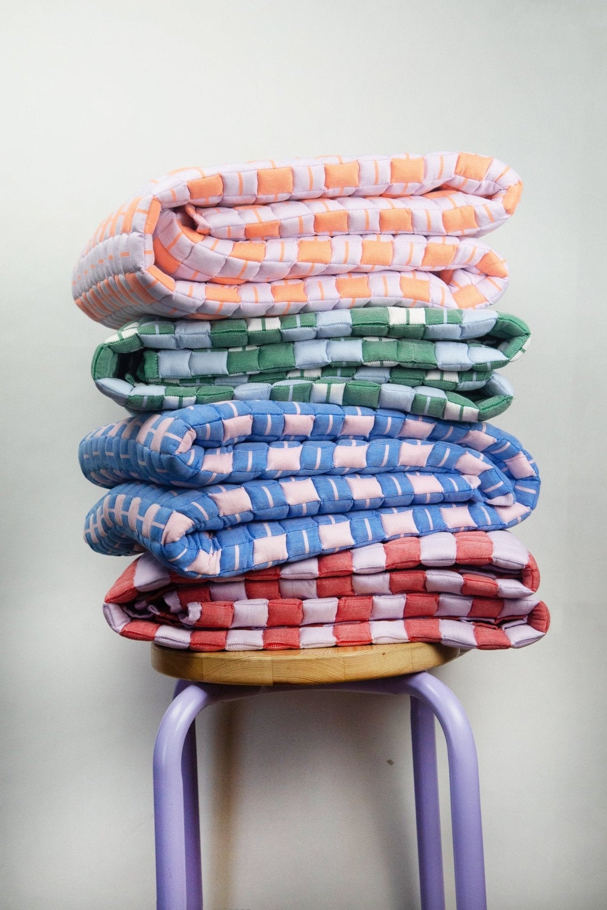 Stack of handwoven quilted Sujani blankets in assorted colors