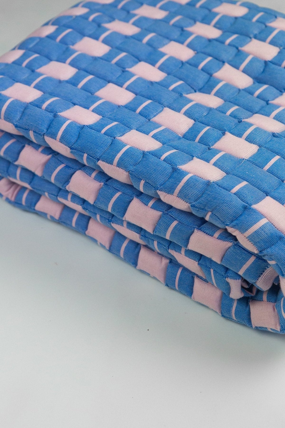 Close-up of the quilted Sujani throw blanket weave in soft pink and blue