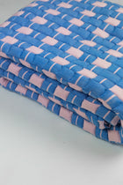 Close-up of the quilted Sujani throw blanket weave in soft pink and blue