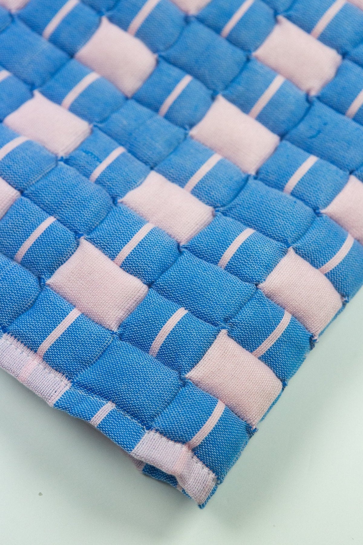 Close-up of the quilted Sujani throw blanket weave in soft pink and blue