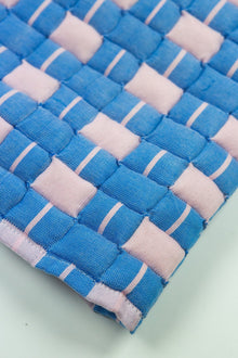 Close-up of the quilted Sujani throw blanket weave in soft pink and blue