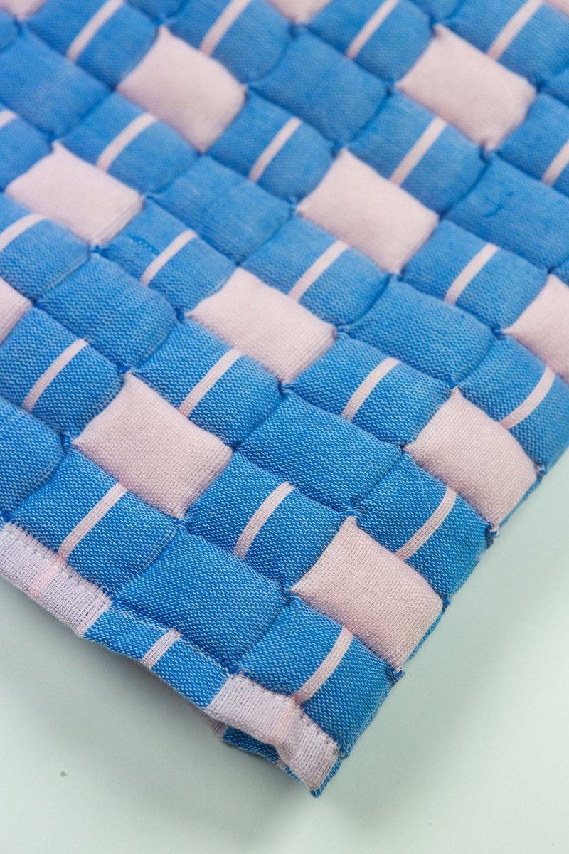 Close-up of the quilted Sujani throw blanket weave in soft pink and blue
