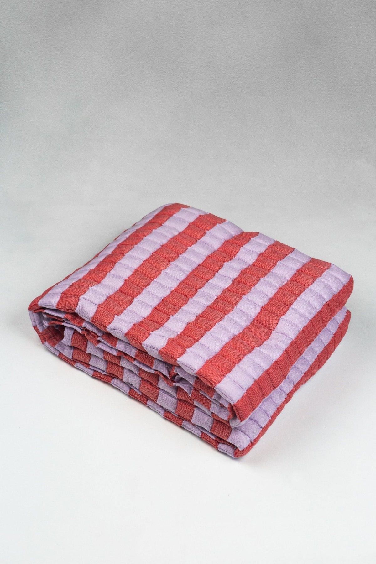 Quilted Sujani throw blanket in soft lilac and red, folded