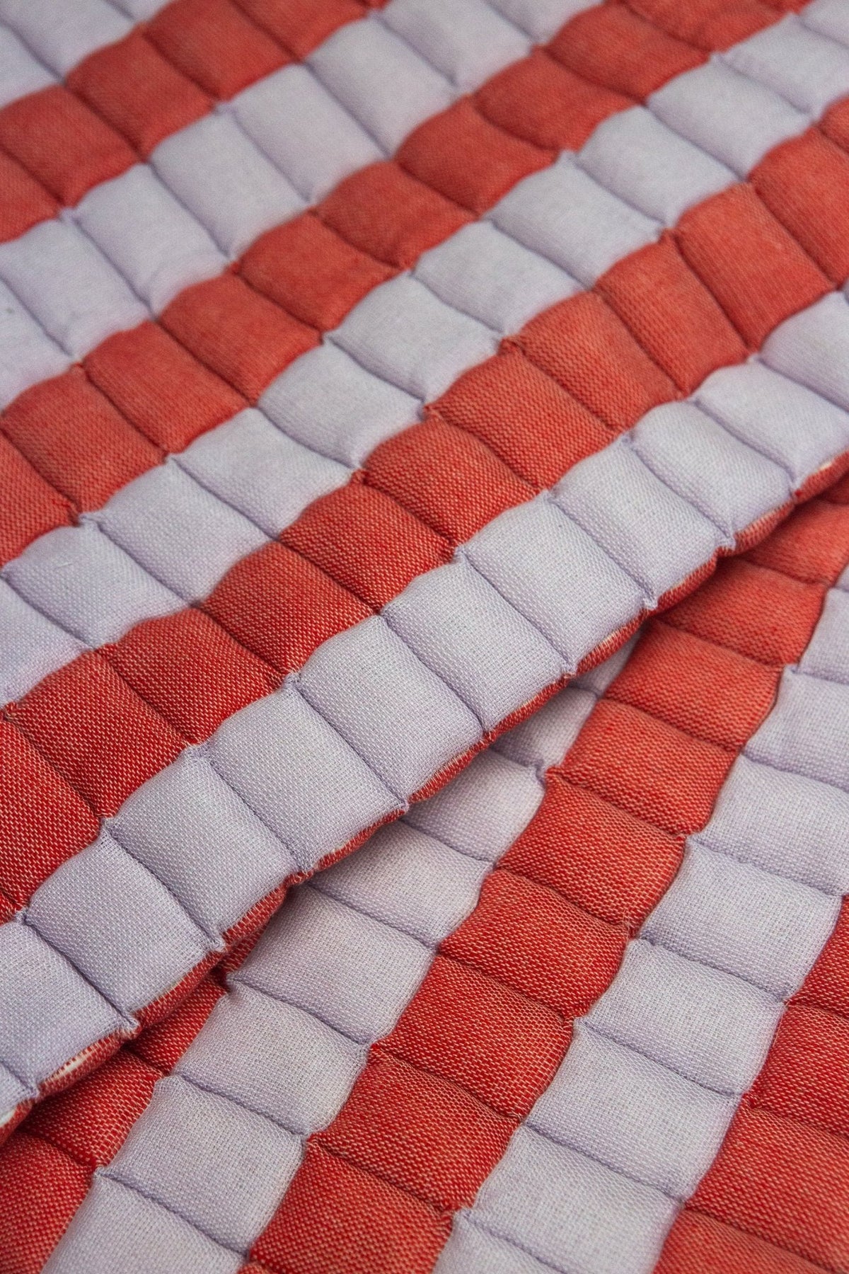 Close-up of the quilted Sujani throw blanket weave in soft lilac and red