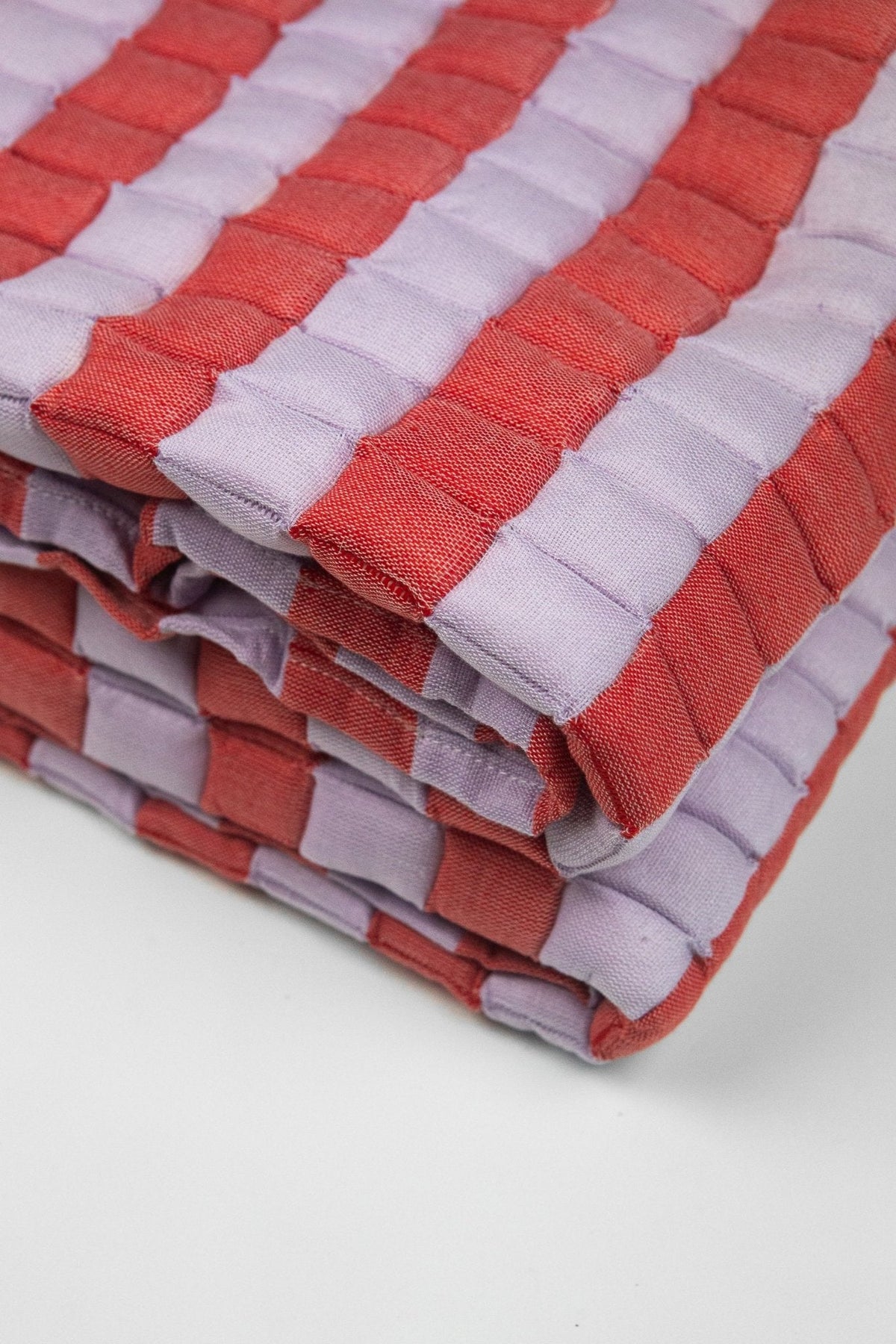 Close-up of the quilted Sujani throw blanket weave in soft lilac and red