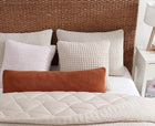 Lumbar and throw pillows in waffle fabric styled on bed
