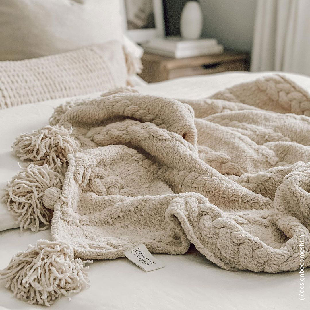 Double-knit Snug throw with pom pom trim styled in living room