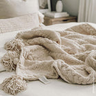 Double-knit Snug throw with pom pom trim styled in living room