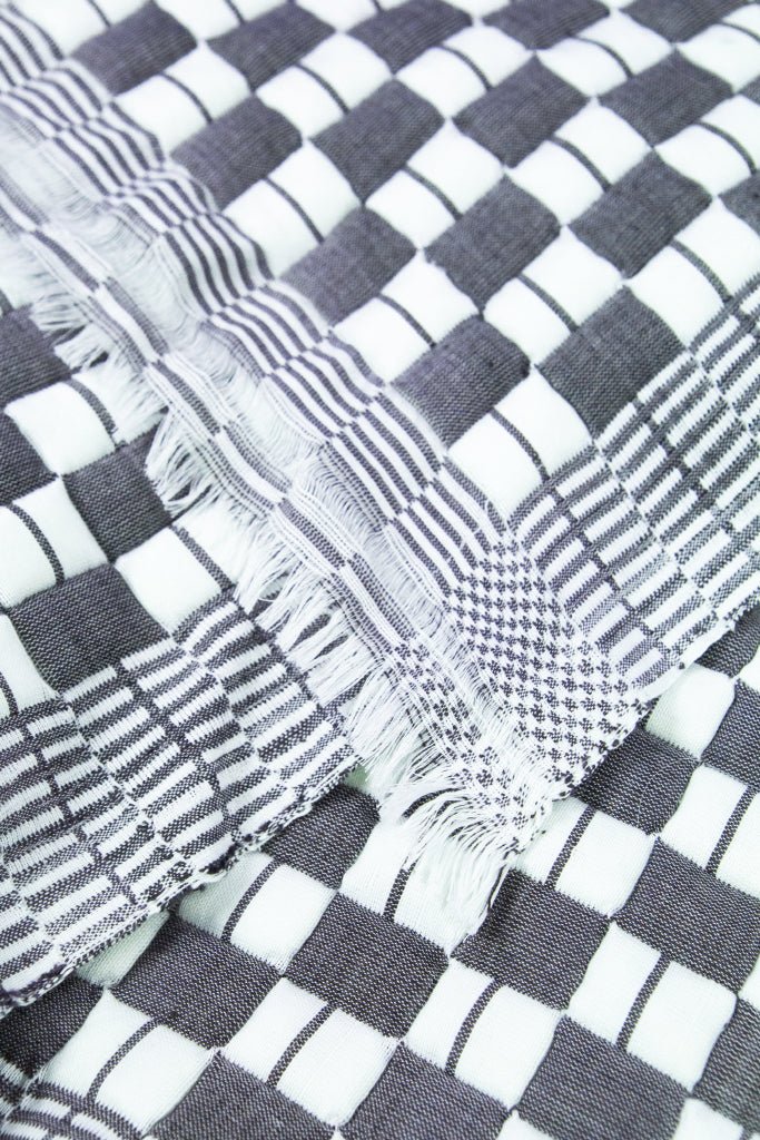 Close-up of the quilted Sujani throw blanket weave in soft black and white