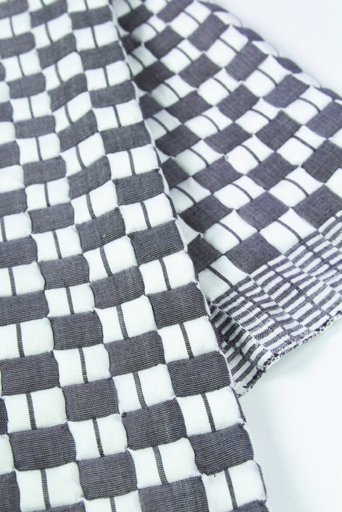 Close-up of the quilted Sujani throw blanket weave in soft black and white
