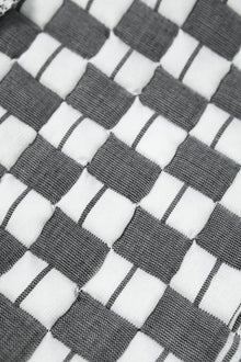 Close-up of the quilted Sujani throw blanket weave in soft black and white